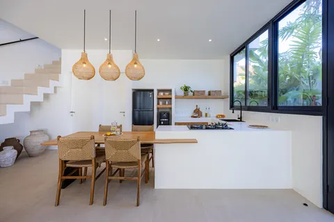 Dining table and kitchen island under three rattan pendants