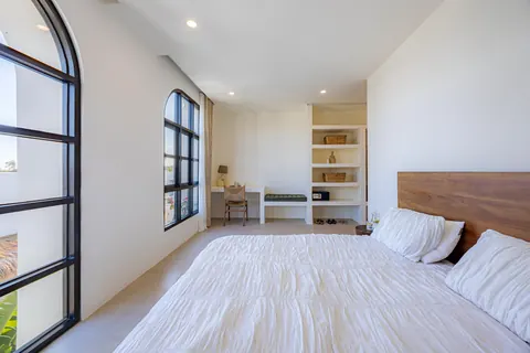 Bedroom with a large arched black-framed window