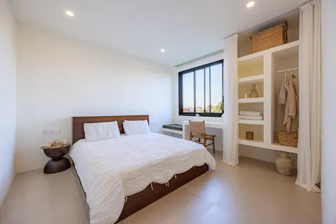 Bedroom with timber bed, built-in desk and a window over the village rooftops
