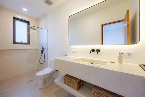 Bathroom with backlit mirror, stone vanity and walk-in shower