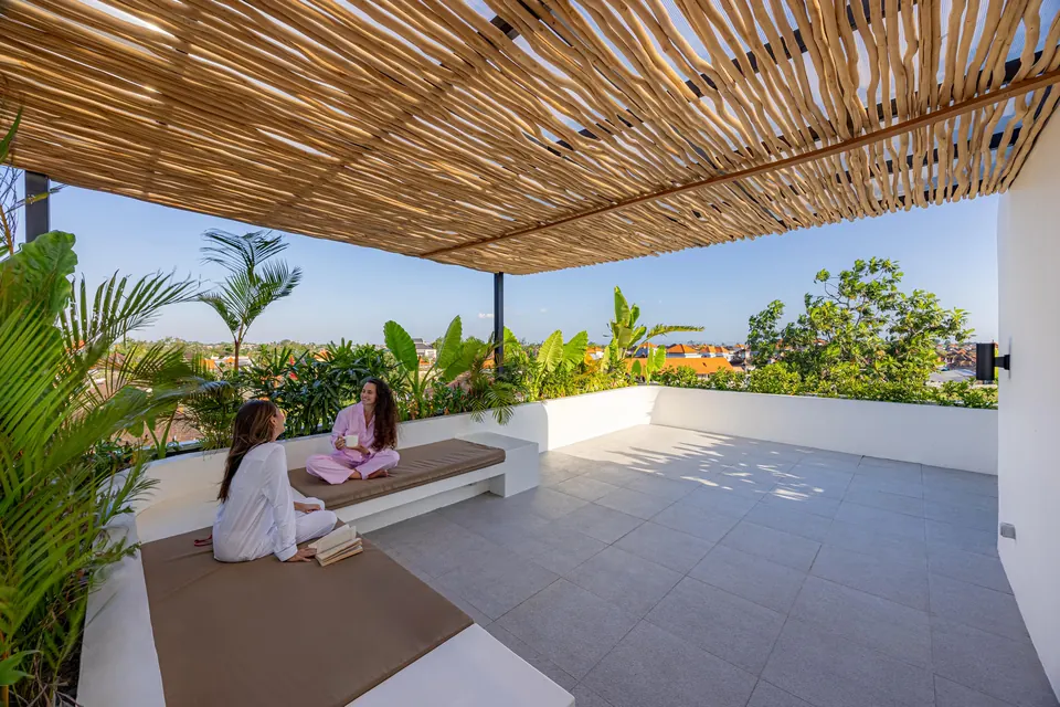 Two people relaxing on the rooftop under a stick pergola